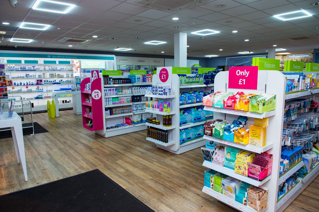 Bright, well-lit interior of an independent community pharmacy with wooden flooring and neatly stocked retail shelving