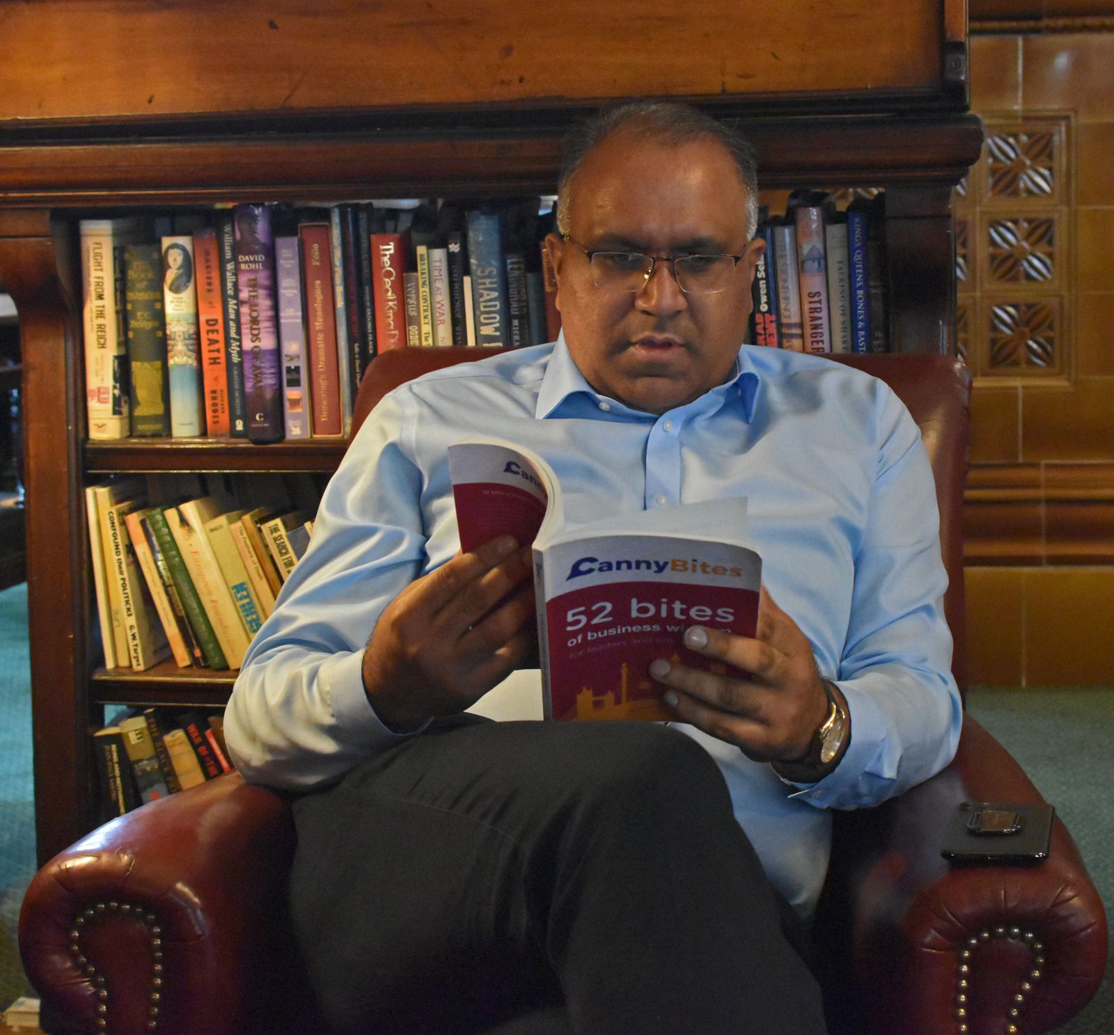 Safaraz Ali MBE reading in a library