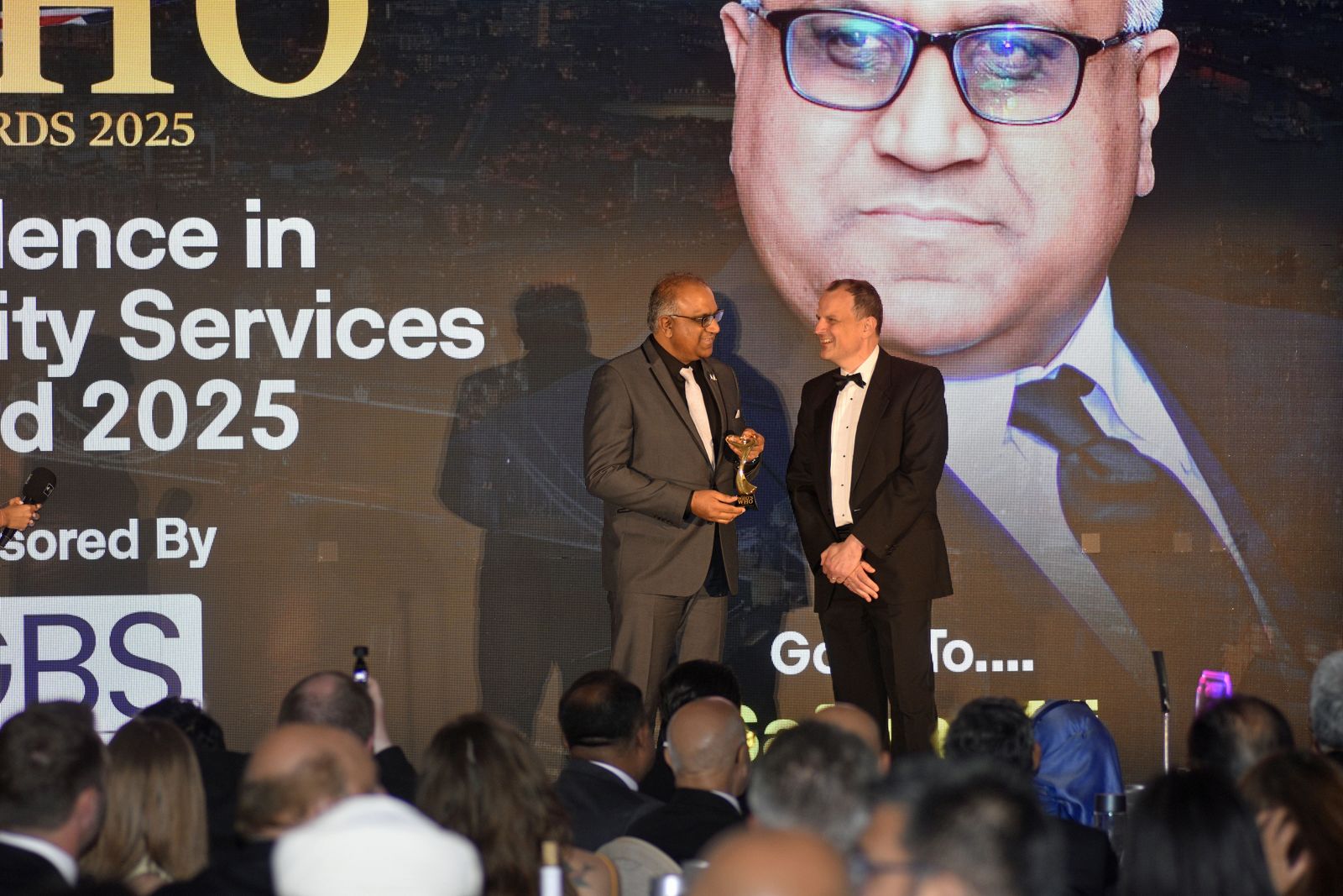 Safaraz Ali MBE on stage at an awards ceremony
